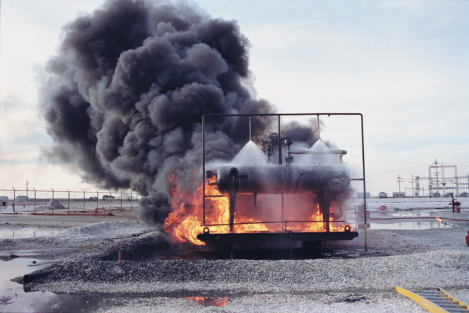 化工罐防火试验:安装在水管上的两个螺旋消防喷嘴向被火焰包围的小型化工罐喷洒大量的水gydF4y2Ba
