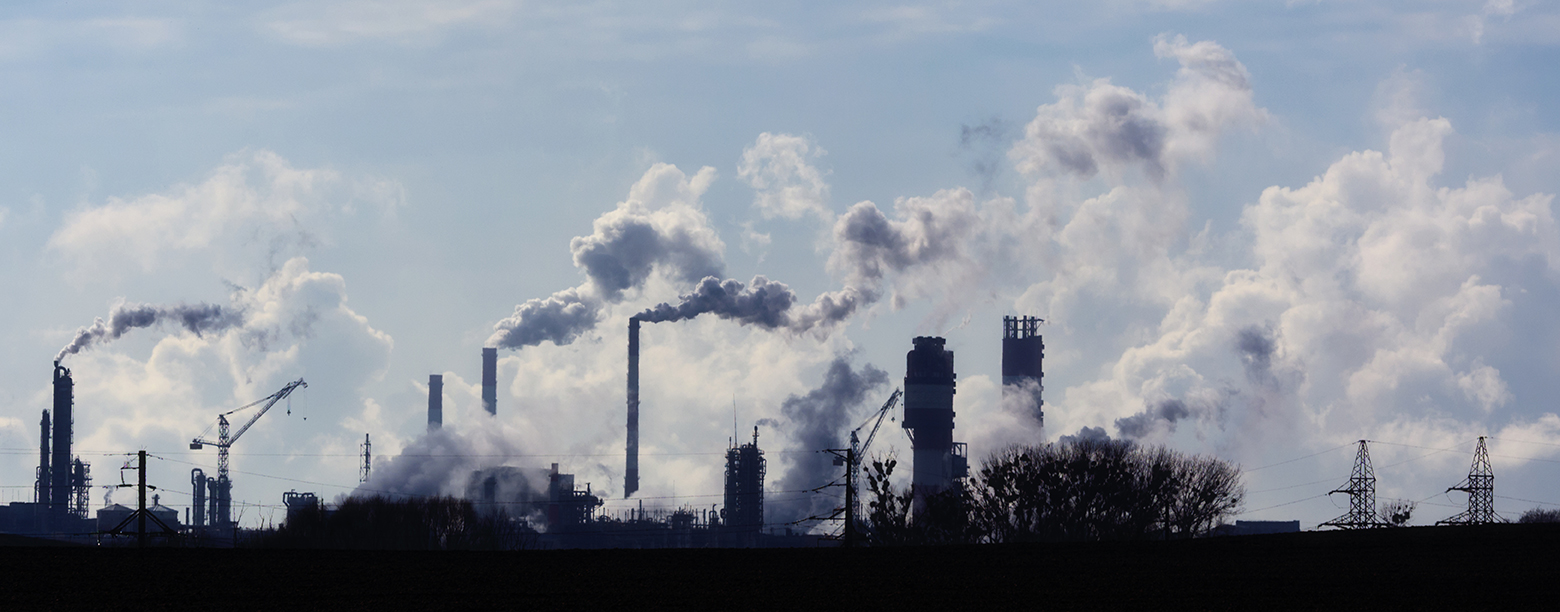 A processing plant with quality-controlled air pollution plumes of smoke and steam coming out of factory chimneys.