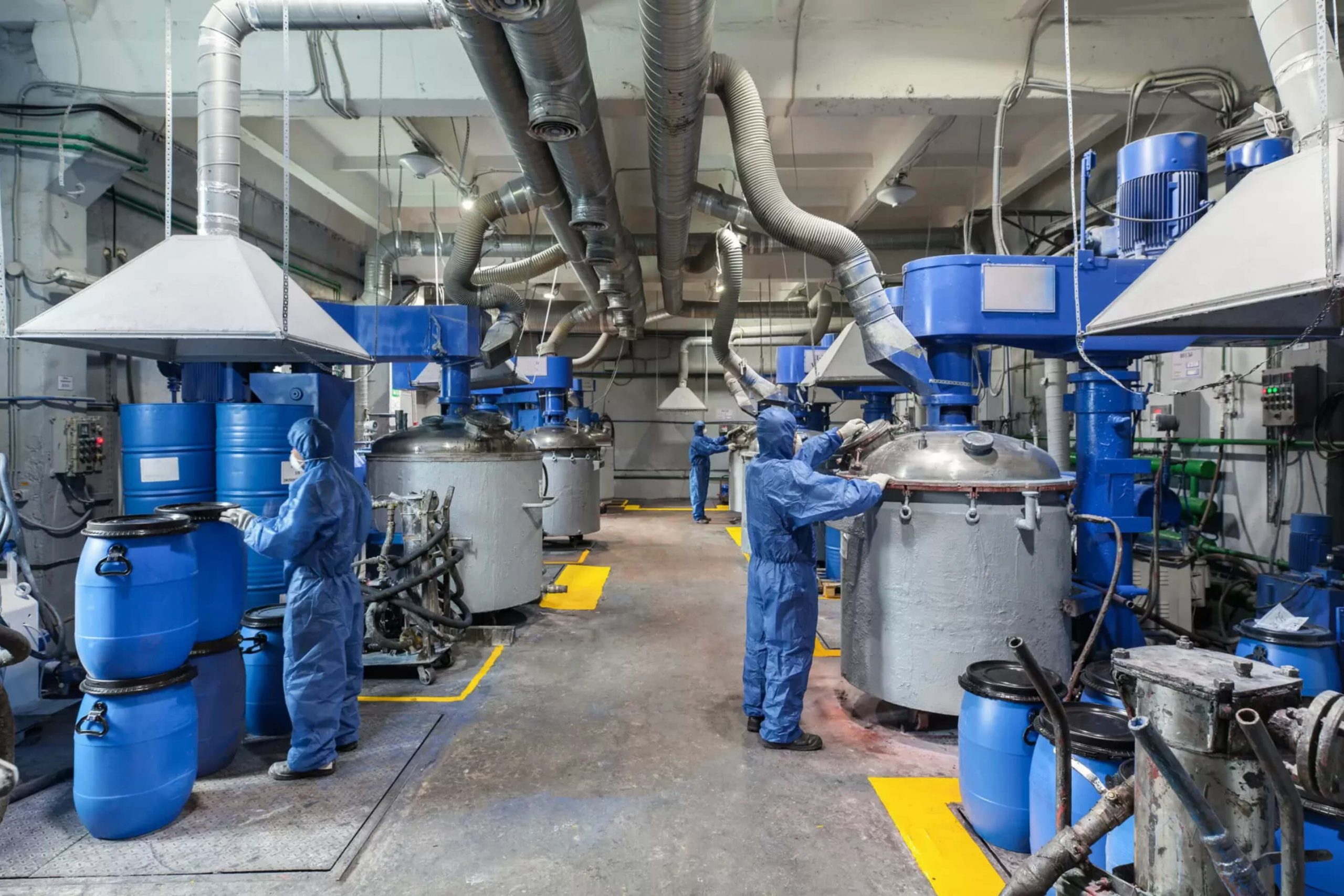 Detail of Workers in blue protective suits at a chemical processing plant.