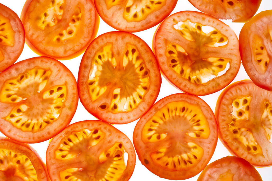 A photograph of tomato slices on a white surface
